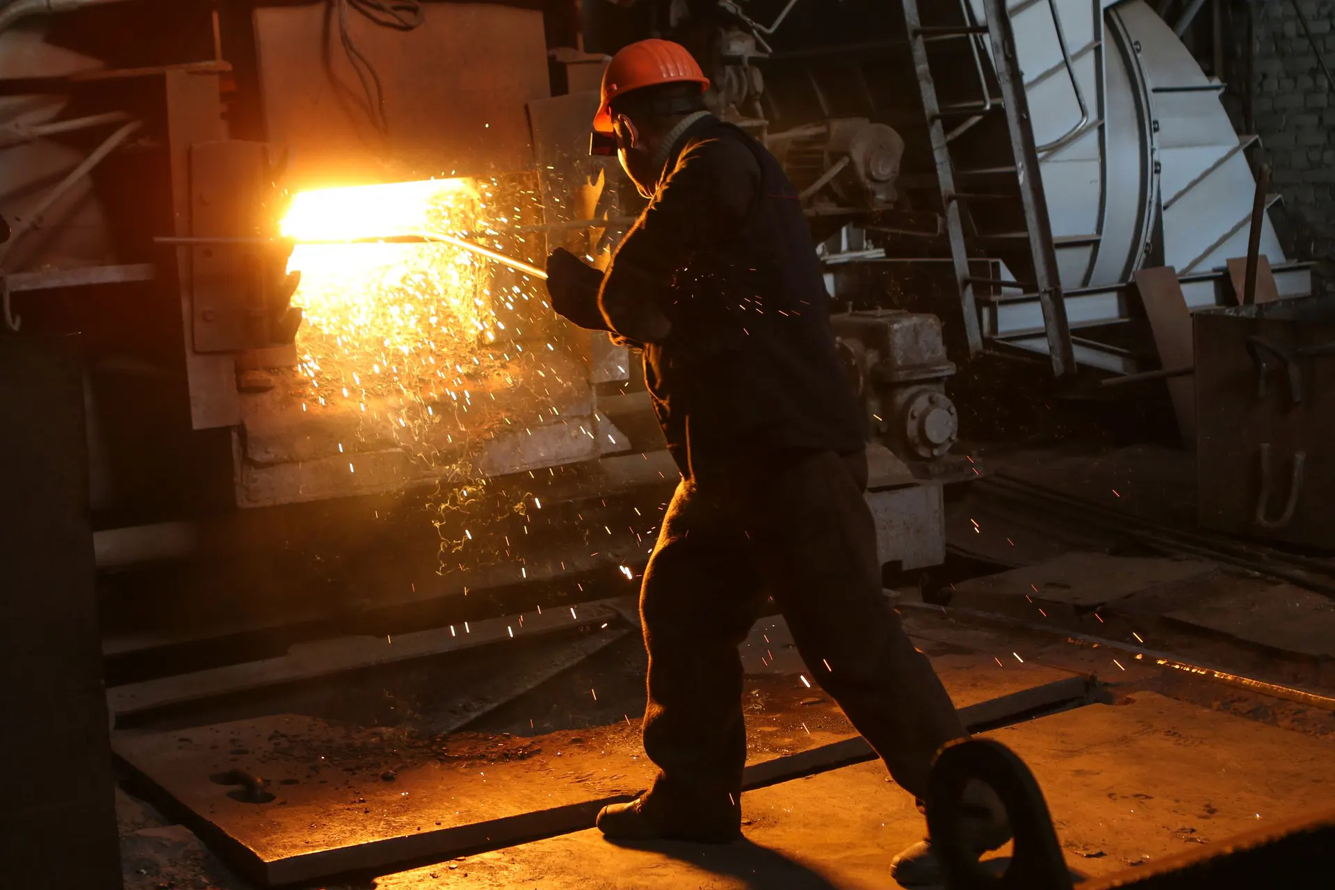 Metal üretim tesisinde ısıl proses yakınında çalışan koruyucu ekipmanlı görevli