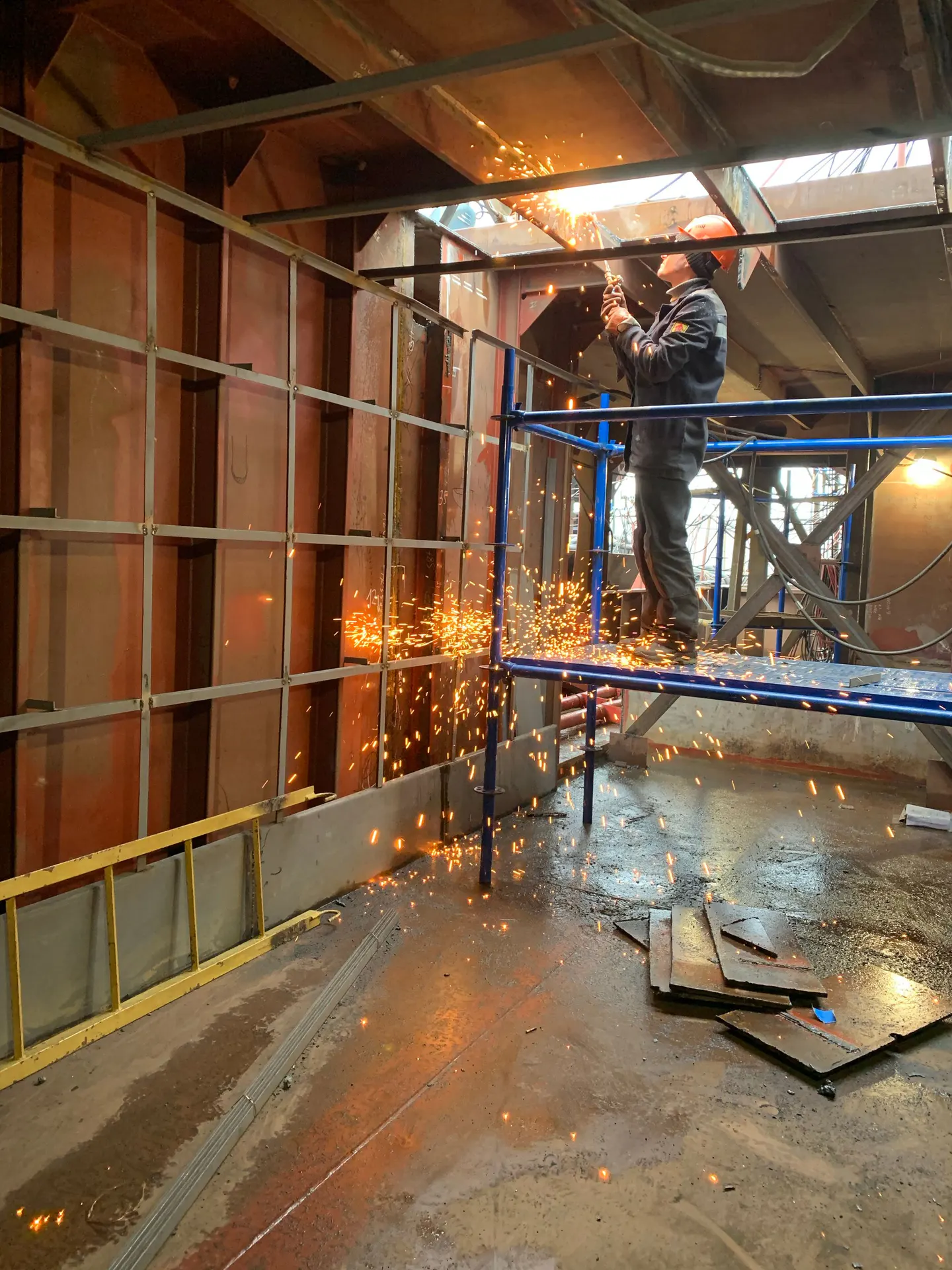 Metal konstrüksiyon üzerinde kesim işlemi yapan koruyucu ekipmanlı çalışan